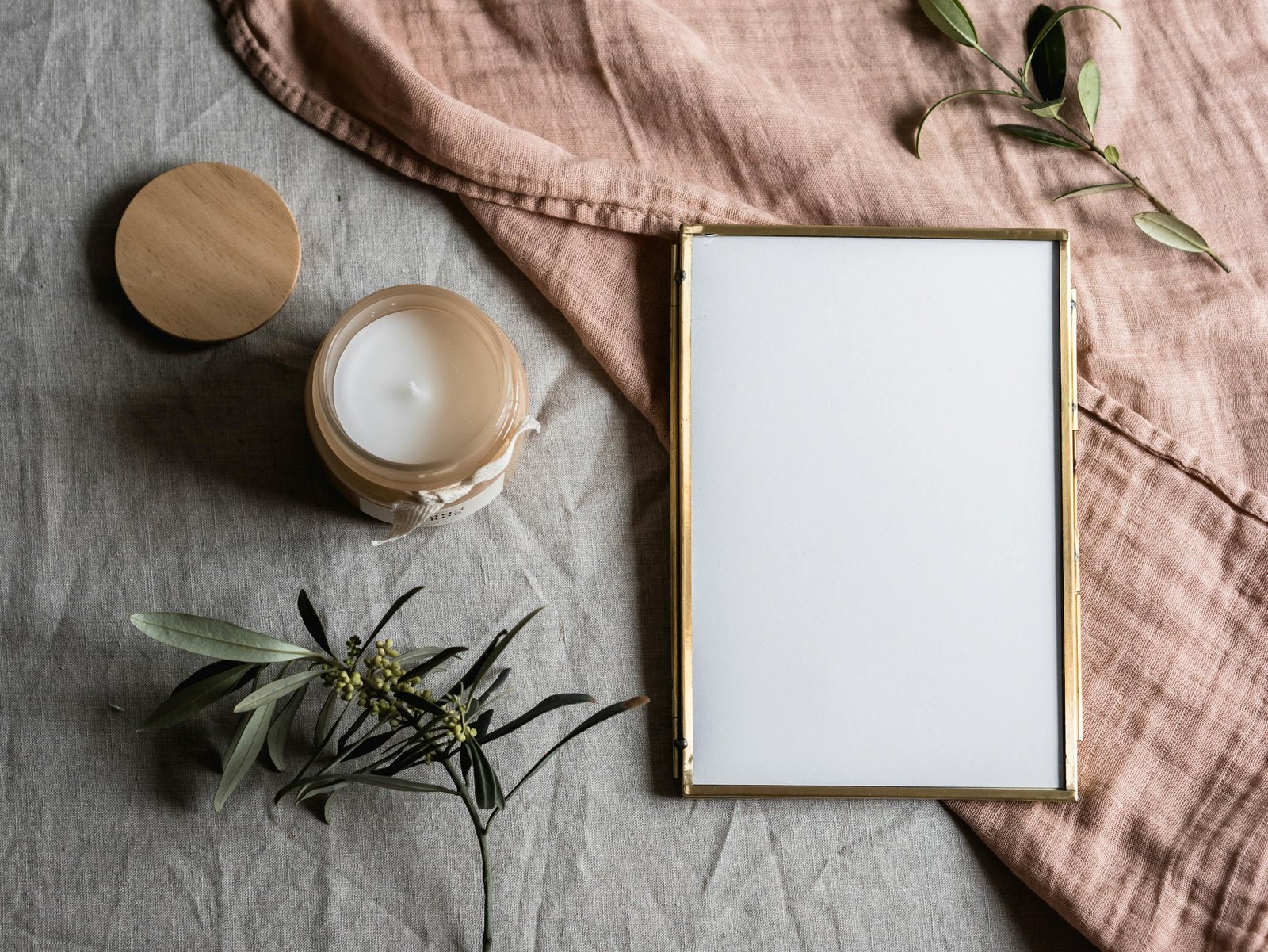 Elegant minimalistic still life composition with candle, frame, and leaves.