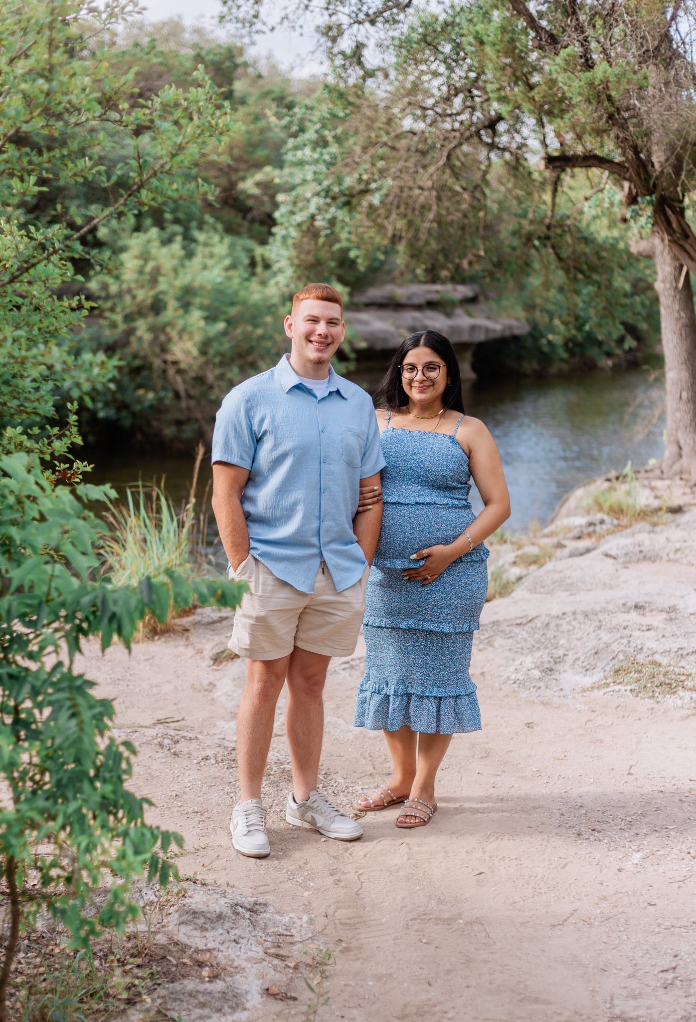Couple holding hands and posing for maternity photos