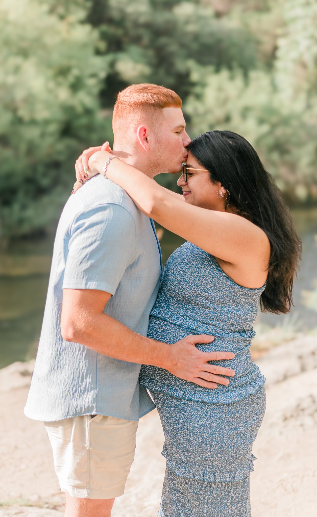 Couple hugging while husband holds his wife's pregnant stomach