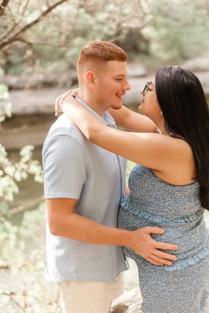Couple smiles at each other while posing for maternity session