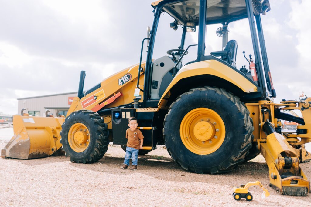 Toddler poses in front of tractor during birthday photoshoot