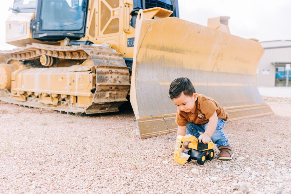 During birthday photoshoot toddler plays with toy tractor