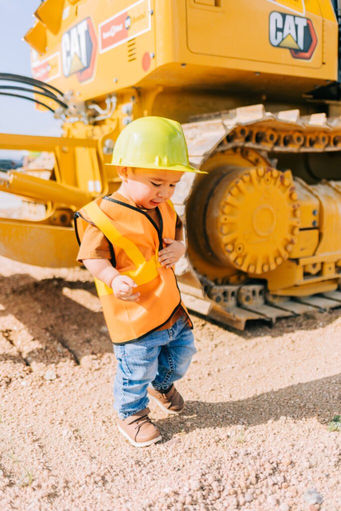 Toddler putting on construction hat during birthday photoshoot