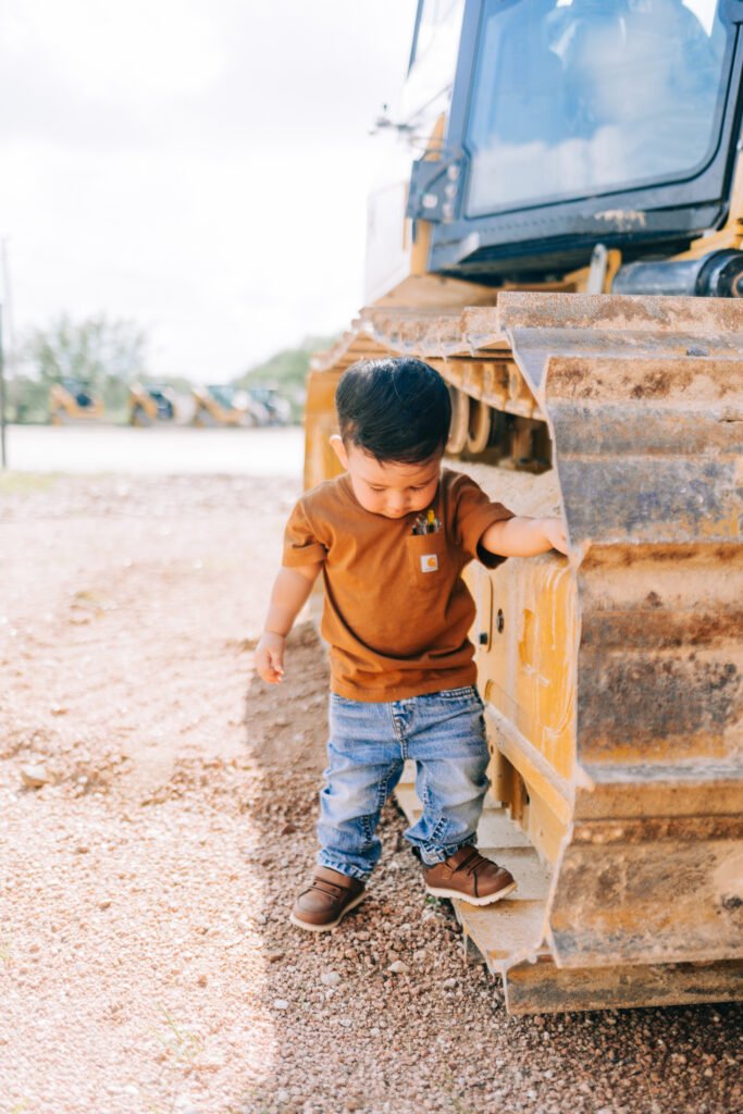 Toddler standing beside tractor during birthday photoshoot