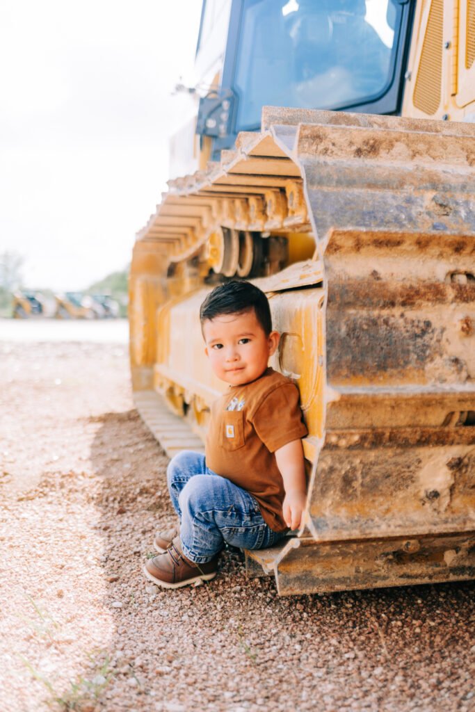 Toddler sitting beside tractor during birthday photoshoot