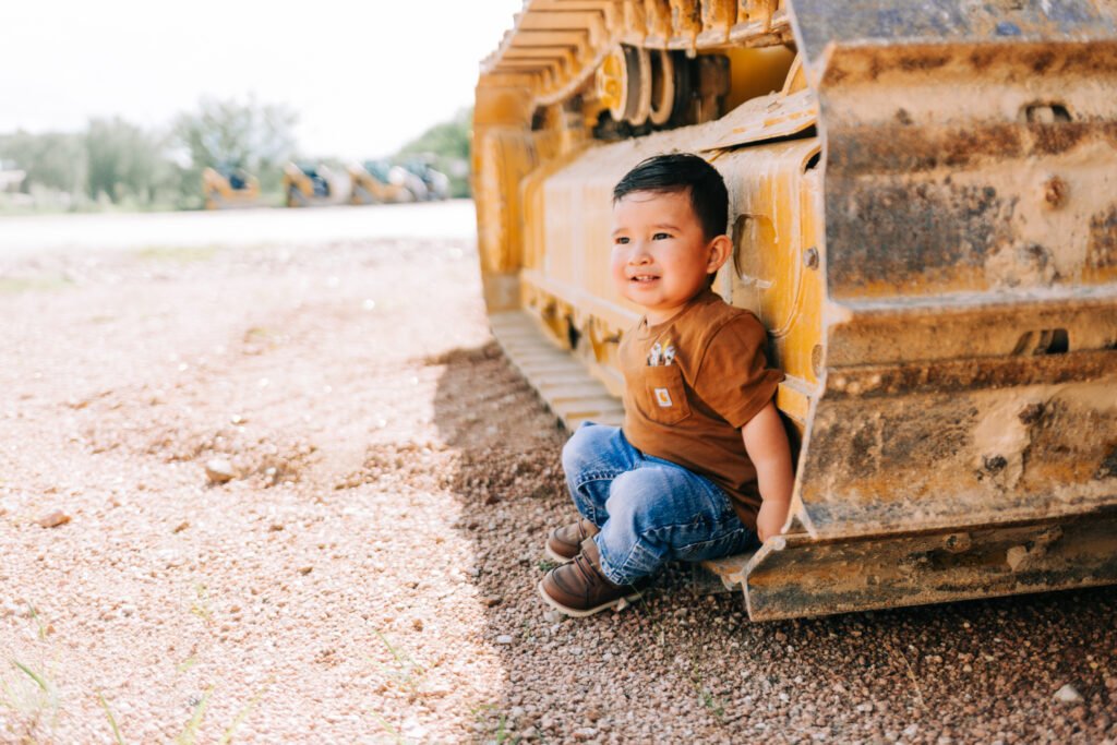 Toddler sitting beside tractor during birthday photoshoot