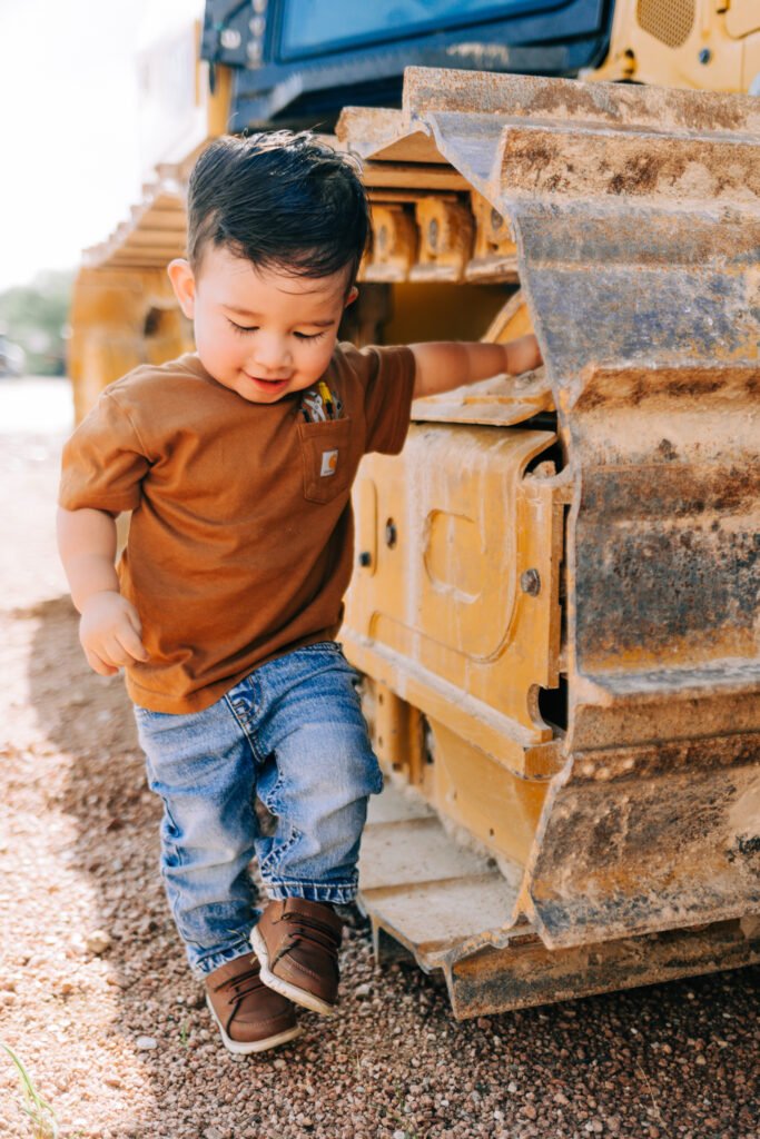 Young boy posing in front of tractor for birthday photoshoot