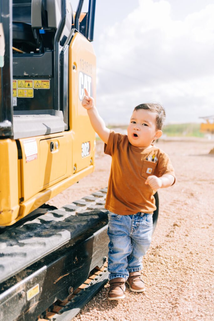 Toddler pointing at tractor during birthday photoshoot