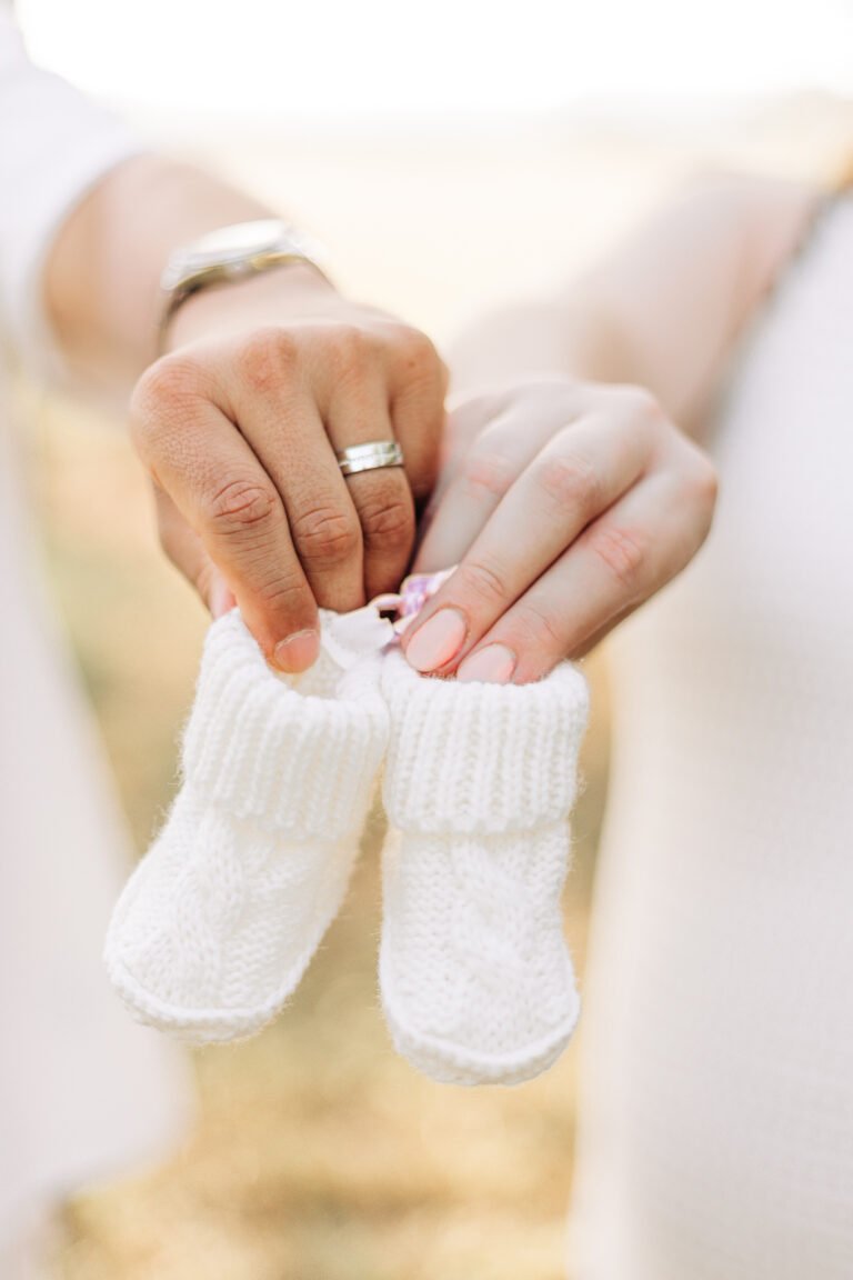 Couple holds baby shoes in maternity session in Buffalo Gap, Tx
